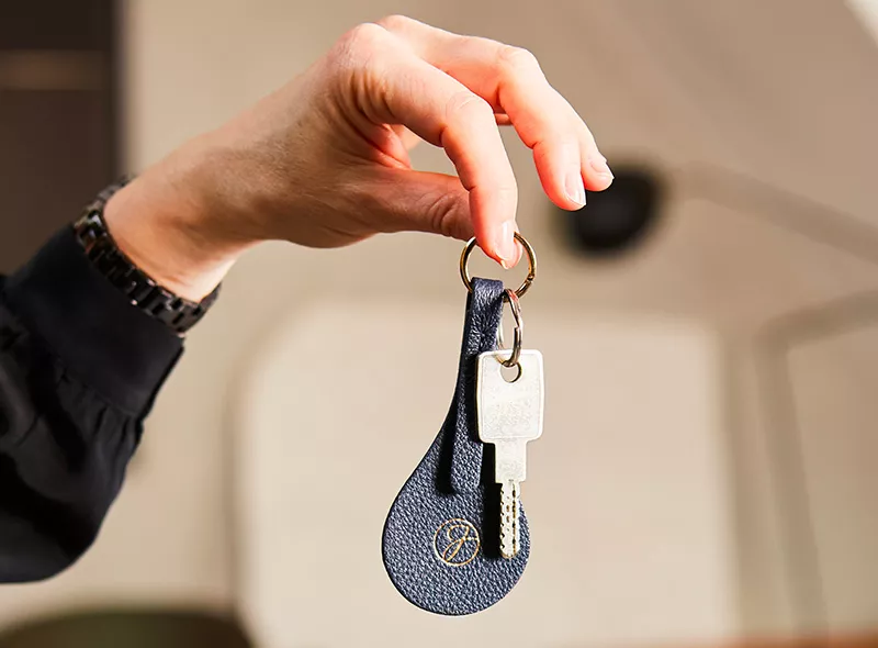 Hand holding the keys to a luxury mansion