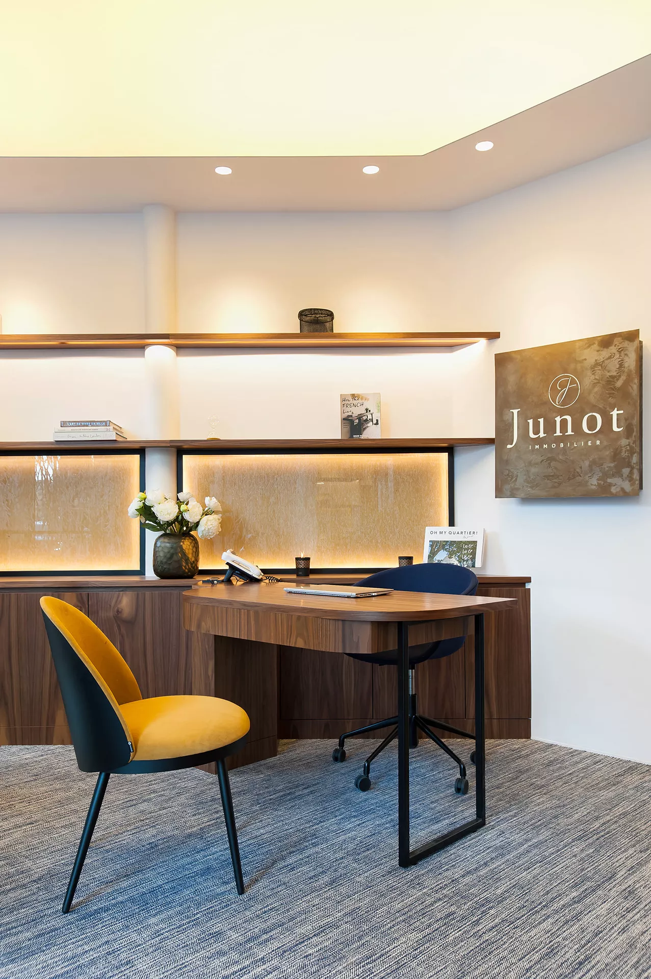 Interior of a Junot agency, view of a brown wooden desk and orange chair